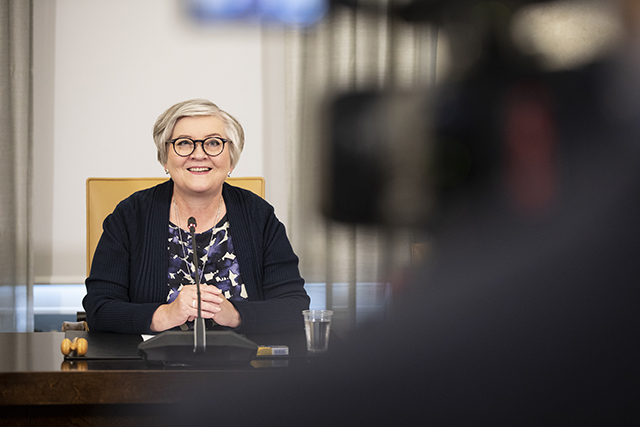 Puhemie Anu Vehviläinen katsoo Eduskuntatalon Arkadia-salissa verkkolähetyskameraan, joka näkyy kuvassa etualalla. 